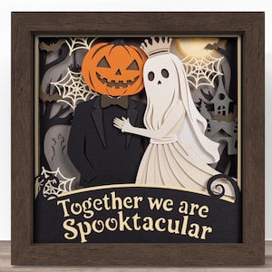 May include: A layered paper shadow box art piece in a dark wood frame featuring a pumpkin-headed figure in a suit and a ghost wearing a crown. The background displays spiderwebs, bats, and a haunted house. The text reads, Together we are Spooktacular.