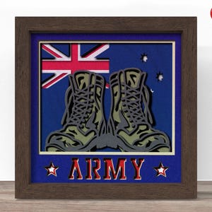 Op de afbeelding: Een ingelijst kunstwerk met een gelaagd ontwerp. Het toont militaire laarzen voor een Australische vlag. Het woord "ARMY" wordt in rode letters onderaan weergegeven, met steraccenten. De laarzen zijn olijfgroen en grijs.