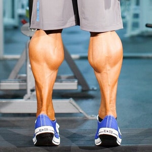 May include: A close-up of a person's legs wearing blue sneakers with the text "All-Star" on them. The person has very defined calf muscles.