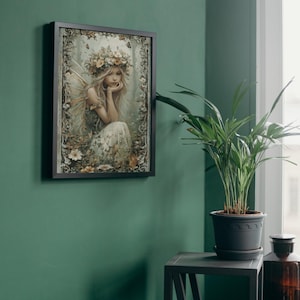 May include: A framed art print featuring a fairy with long blonde hair, a floral crown, and delicate wings. The fairy is seated amidst flowers and foliage, with a soft, ethereal color palette. The frame is black, and the artwork is displayed on a green wall.