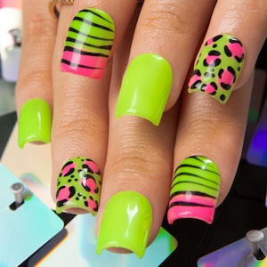 May include: A hand displaying a set of manicured nails. The nails feature a neon green base with designs including pink and black zebra stripes, leopard spots, and solid neon green. The nail art is vibrant and eye-catching.