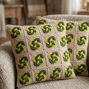 Peut inclure: Deux coussins carrés au crochet avec un fond beige et des motifs de nœuds celtiques verts et vert citron. Les coussins sont sur un canapé de couleur neutre. Le travail au crochet est détaillé et les coussins semblent doux et confortables.