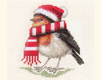 May include: Cross-stitch image of a robin bird wearing a red and white striped scarf and a matching hat. The bird has a brown breast, gray and black wings, and is standing on a patch of green. The background is a light beige color.