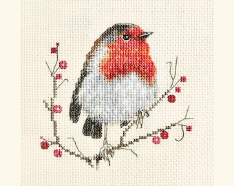 May include: Cross-stitch embroidery of a European robin bird perched on a branch with red berries. The bird has a red breast, gray and white feathers, and black accents. The background is a cream-colored fabric.