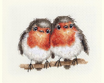 May include: Cross-stitch of two robins perched on a brown branch. The birds have red breasts, gray and brown wings, and black eyes. The background is a cream-colored fabric.