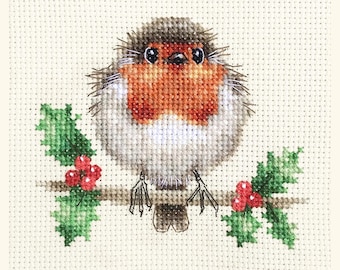 May include: Cross-stitch image of a round robin bird with a red breast, perched on a brown branch with green holly leaves and red berries. The bird has gray and brown feathers and is set against a cream-colored background.