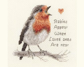 May include: Cross-stitch embroidery of a robin perched on a branch, with a red breast and gray and black wings. The text reads "Robins Appear When Loved Ones Are Near" with a small heart above the text.