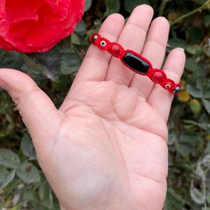 Peruvian protection bracelet with a natural rectangular Black Obsidian, 2 Red Jade, 2 Hematite beads and evil eyes woven onto a black cord.