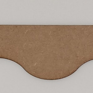 May include: A brown wooden scalloped trim with a wavy edge. The trim is about 1 inch wide and 12 inches long.
