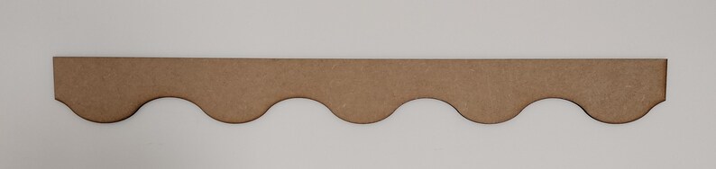 May include: A brown wooden scalloped trim with a wavy edge. The trim is about 1 inch wide and 12 inches long.