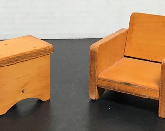May include: A set of two wooden dollhouse furniture pieces: a small stool and a chair. Both pieces are made of light brown wood and have a simple, rustic design.