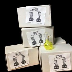 May include: Four white boxes with black text that reads "Concord Miniature Glass Pitcher" and a small yellow glass pitcher with a handle.