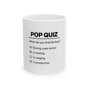 May include: White ceramic mug with the text "POP QUIZ" and a multiple-choice question about finding bugs in software development. The mug has a cylindrical shape and a simple design.