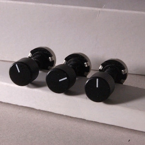 Peut inclure: Trois boutons de commande noirs avec un trait indicateur blanc. Les boutons ont une forme cylindrique avec une texture stri&eacute;e sur les c&ocirc;t&eacute;s. La base de chaque bouton est argent&eacute;e.