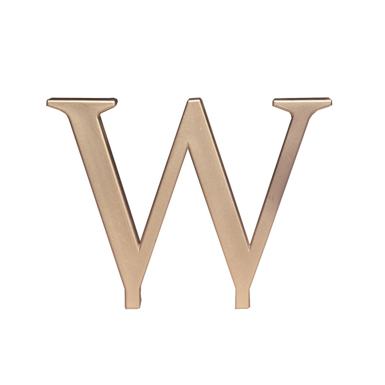 以下が含まれることがあります： 金色の金属製のアルファベットのW。文字は白い背景に立っています。