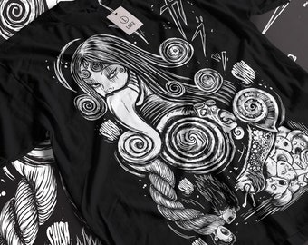 May include: Black t-shirt with a white graphic print of a woman with multiple eyes and a spiral pattern. The graphic also includes a rope and the word "SHSH".