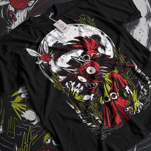 Puede incluir: Camiseta negra con una ilustración roja y blanca de un monstruo con cuernos y un ojo grande. El monstruo está de pie frente a una luna llena con una pequeña criatura alada que sostiene una rosa roja.