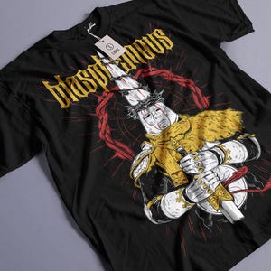 Könnte beinhalten: Schwarzes T-Shirt mit einem Grafikdruck einer Figur, die eine Dornenkrone trägt und ein Schwert hält. Der Text "Blasphemous" ist in Weiß auf dem Shirt gedruckt.