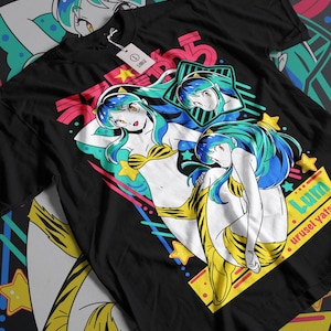 Puede incluir: Camiseta negra con un diseño gráfico colorido que presenta a una mujer con cabello azul y verde usando un traje de baño a rayas amarillo y negro. El gráfico también incluye estrellas, rayas y el texto "Lum urusei yatsu".