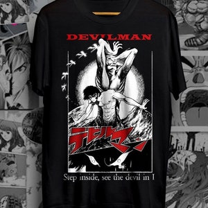 May include: Black t-shirt with a white graphic of a man with devil wings. The graphic includes the text "DEVILMAN" and "Step inside, see the devil in I".