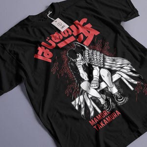 May include: Black t-shirt featuring a manga-style illustration of a person with wing-like elements, seated and contemplative. Red Japanese text and the name "MAMORU TAKAMURA" are also visible. A white tag is attached.
