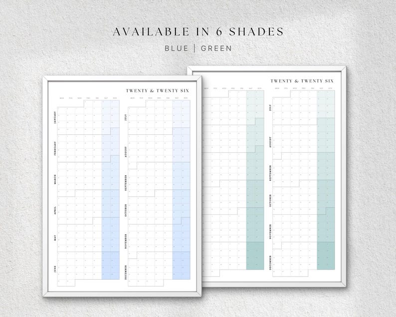 K&ouml;nnte beinhalten: Zwei gerahmte Jahreskalender, einer blau und einer gr&uuml;n, mit dem Text "AVAILABLE IN 6 SHADES" oben. Die Kalender sind mit "TWENTY & TWENTY SIX" beschriftet und zeigen Monate und Daten. Der Hintergrund ist hellgrau.