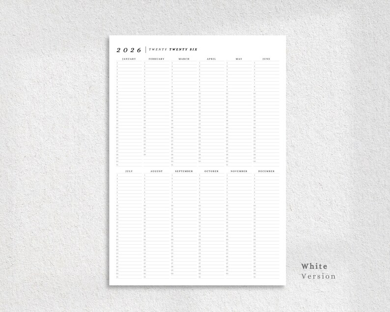 May include: A white 2026 yearly planner with a minimalist design. The planner features a clean layout with columns for each month and space for daily entries. The text "2026 Twenty Twenty Six" is at the top. The words "White Version" are at the bottom right.