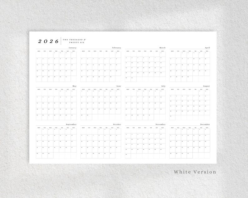 May include: A minimalist white 2026 yearly calendar with a grid layout. The calendar displays all twelve months, with each month's days arranged in a grid. The year 2026 is displayed at the top left, with the text "TWO THOUSAND & TWENTY SIX" next to it.