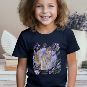 May include: A navy blue t-shirt with a watercolor illustration of a wolf standing in front of a crescent moon surrounded by purple flowers.