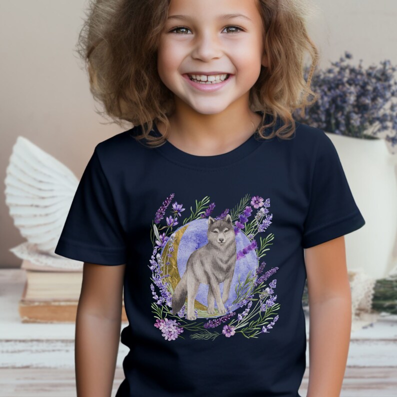 May include: A navy blue t-shirt with a watercolor illustration of a wolf standing in front of a crescent moon surrounded by purple flowers.