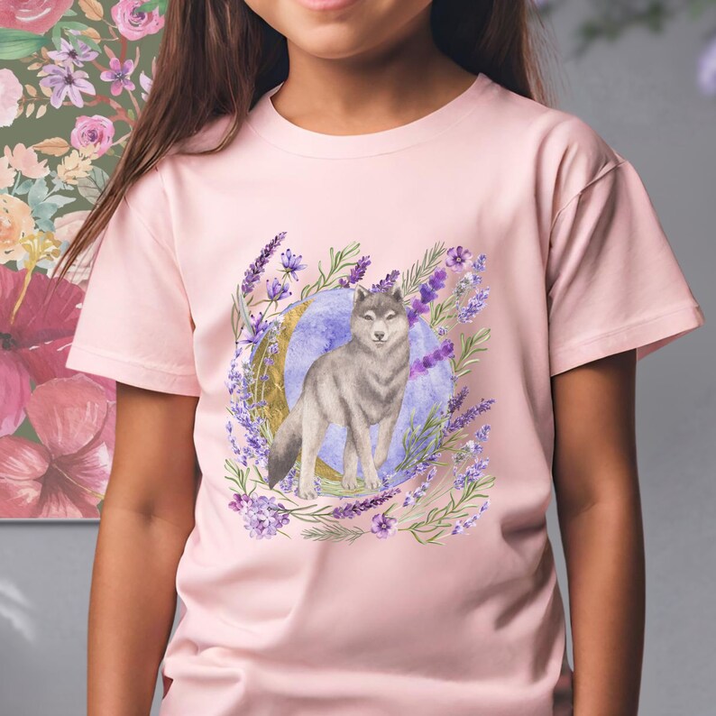 May include: A pink t-shirt with a watercolor design of a wolf standing in a circle of lavender flowers and a crescent moon.