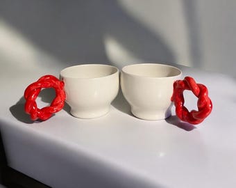 Handgjort keramiskt muggset: Moderna kaffekoppar med röda vridna handtag
