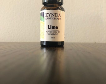 Può includere: Un piccolo flacone di vetro ambrato con un tappo nero, etichettato "ZYNDA APOTHECARY Lime Pure Essential Oil 100% UNCUT 10 ml".