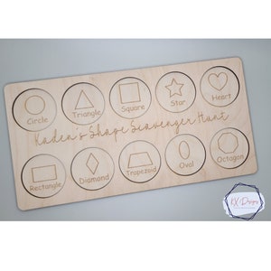 May include: Wooden board with a shape scavenger hunt for kids. The board has 10 different shapes, including a circle, square, triangle, star, heart, diamond, trapezoid, oval, and octagon. The board is labeled "Kaden's Shape Scavenger Hunt".