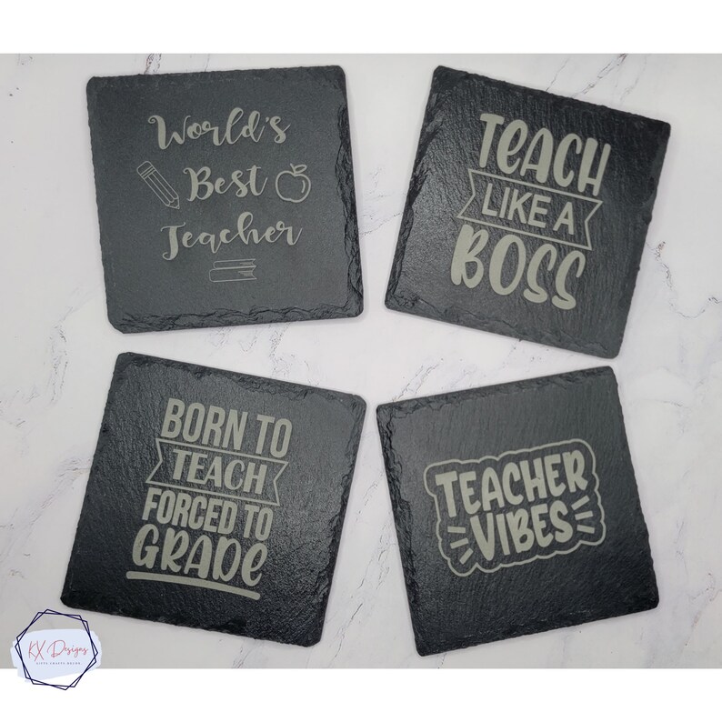 May include: Four black slate coasters with white text. The coasters feature teacher-themed sayings: "World's Best Teacher", "Teach Like A Boss", "Born To Teach Forced To Grade", and "Teacher Vibes".