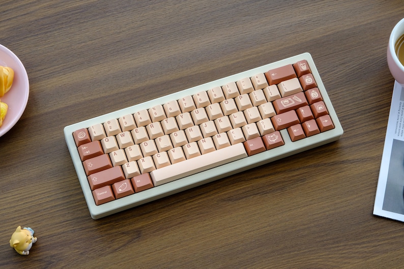 May include: A light beige mechanical keyboard with brown and beige keycaps. The keycaps have various symbols and icons printed on them.