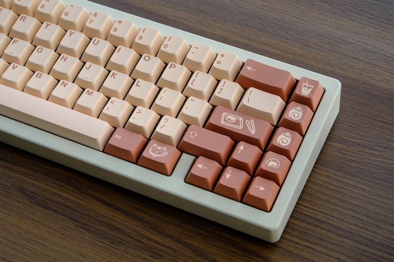 May include: A light green keyboard with beige keys and brown keys with various symbols. The symbols include a cat, a cup of coffee, a pastry, and a pair of chopsticks.