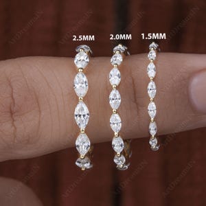 May include: Three gold eternity bands with marquise-shaped diamonds. The bands are shown on a finger and are labeled with their sizes: 1.5mm, 2.0mm, and 2.5mm.