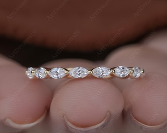 Könnte beinhalten: Ein zarter Goldring mit einer Reihe von weißen Edelsteinen im Marquiseschliff. Der Ring hat ein schlankes, poliertes Goldband, und die Edelsteine sind eng aneinander gesetzt, wodurch ein kontinuierliches Funkeln entsteht. Der Ring ist ein Schmuckstück.