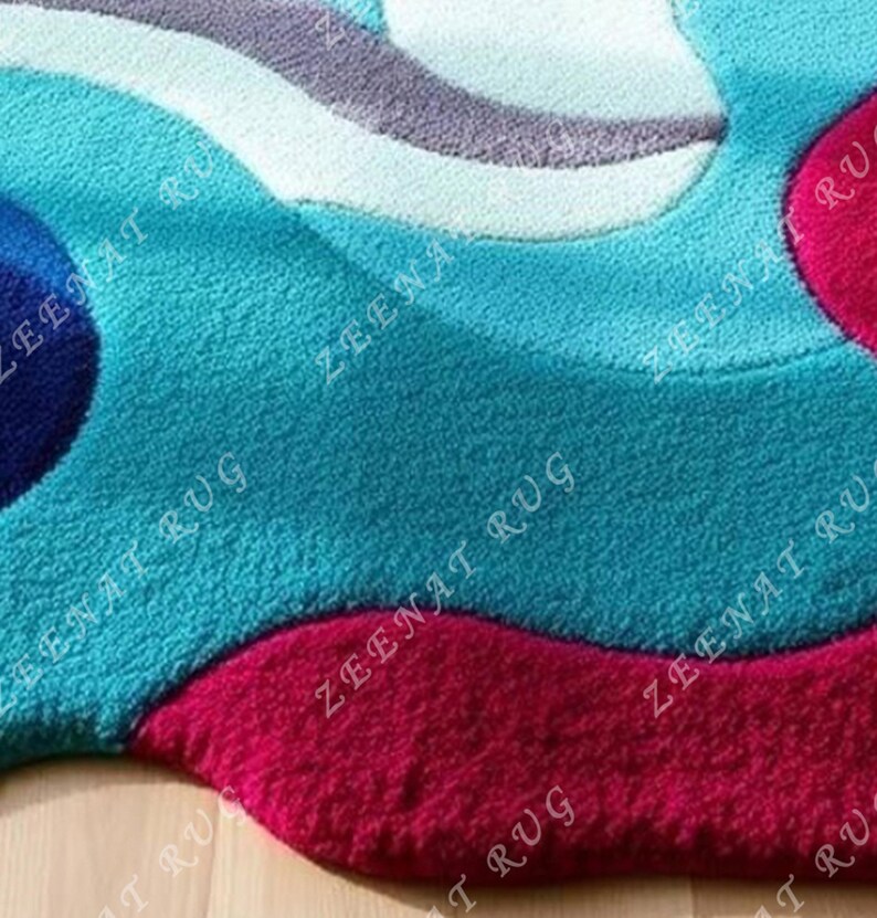 May include: A close-up of a blue and pink abstract area rug with a wavy design. The rug is made of soft, plush material.