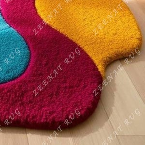 May include: A colorful, abstract rug with a wavy design. The rug is made of a soft, plush material and features shades of blue, red, and yellow.