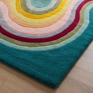Puede incluir: Una alfombra azul turquesa con un dise&ntilde;o de arco&iacute;ris multicolor. La alfombra tiene una textura peluda y est&aacute; hecha de lana.