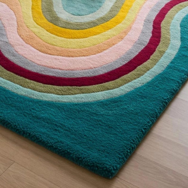 Puede incluir: Una alfombra azul turquesa con un dise&ntilde;o de arco&iacute;ris multicolor. La alfombra tiene una textura peluda y est&aacute; hecha de lana.