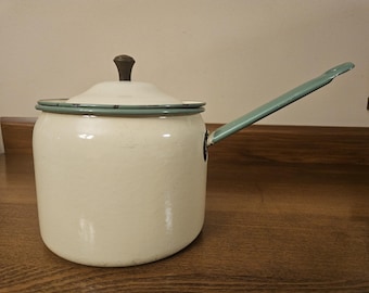 Vintage cream and green enamelware lidded saucepan with a wooden single handle.