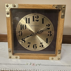 Vintage Quartz Mercedes Wall Mounted Clock Set in Wood Frame with Gold Toned Metal Corners.  Set Behind Glass.  11&quot; x 11&quot;