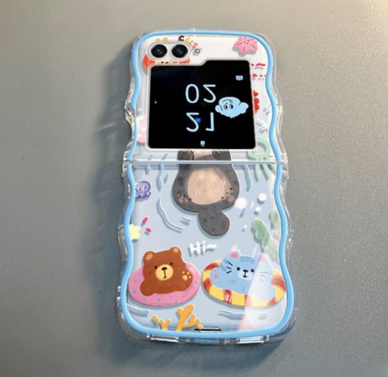 May include: A clear blue phone case with a cartoon otter, bear, and cat design. The case has a built-in flip cover with a digital clock that reads "15:30".