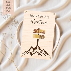 May include: A wooden sign with the text "FÜR DAS NÄCHSTE Abenteuer" and a signpost graphic indicating "50". The signpost has a house and star graphic. The sign is mounted with small metal fasteners.