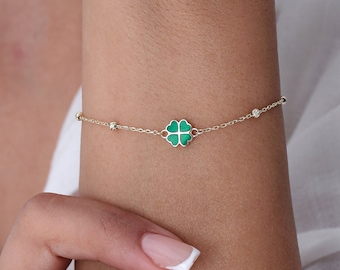 May include: A gold chain bracelet with a green four-leaf clover charm.