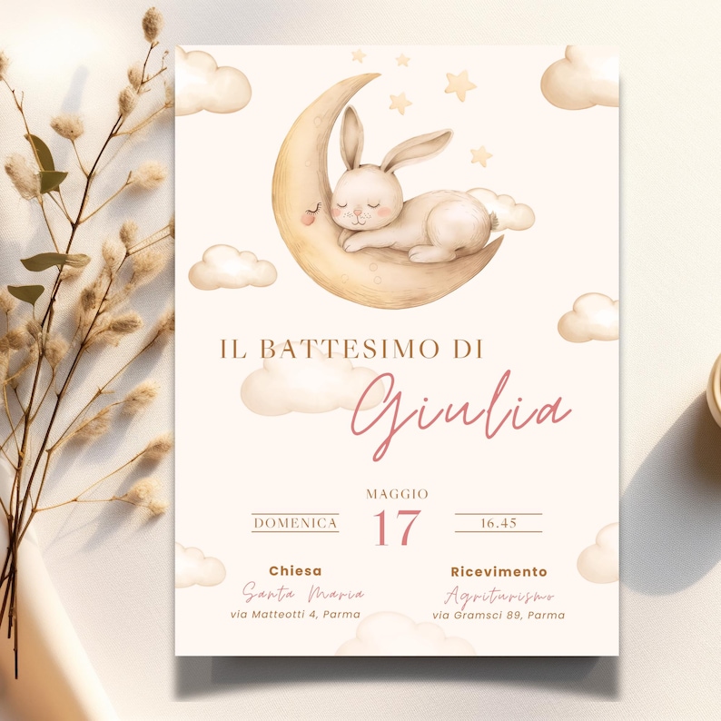 May include: A baptism invitation with a watercolor illustration of a white bunny sleeping on a crescent moon. The text reads "Il Battesimo di Giulia" with the date and time of the event, the church name and address, and the reception location.