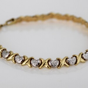 Puede incluir: Pulsera dorada con eslabones alternos en forma de X y coraz&oacute;n. Los corazones tienen un acabado texturizado de color plateado. Una joya delicada, adecuada para el uso diario o ocasiones especiales.